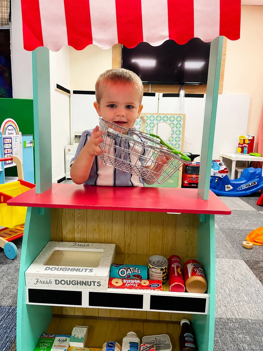 Child playing shopkeeper in the Pop It Play role play area