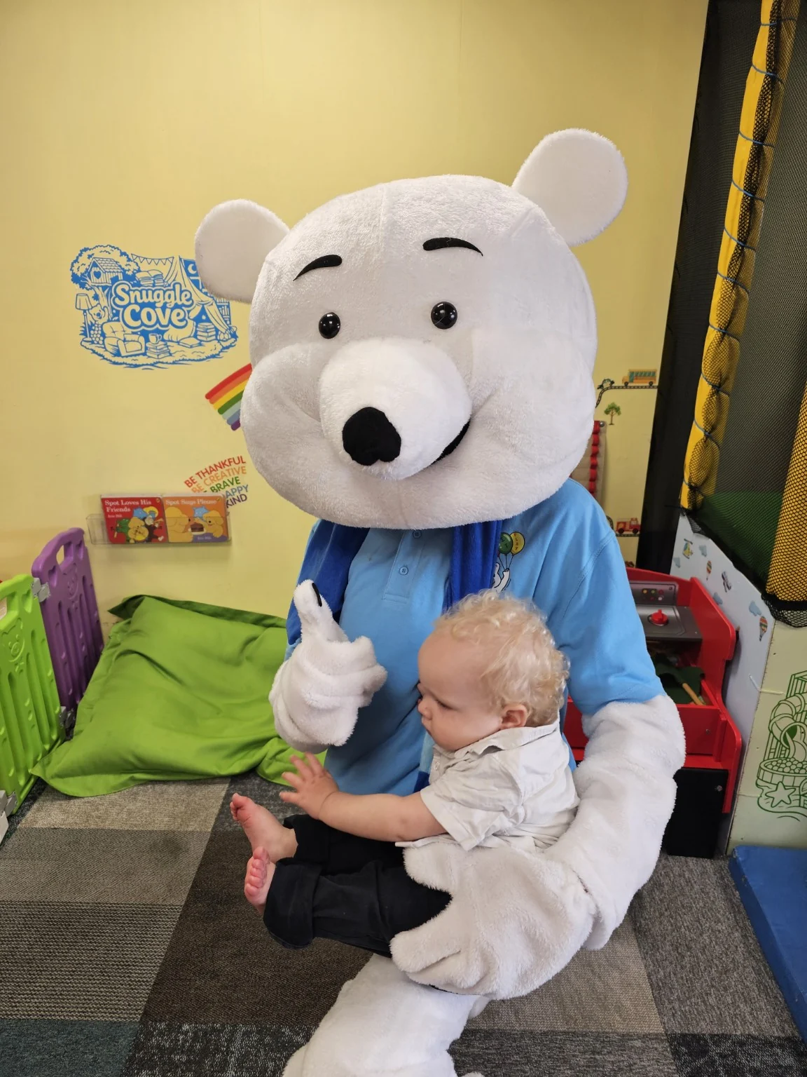 Pip the Pop It Play polar bear mascot sitting with a young child in Snuggle Cove